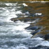 Wasser fliesst in einem Fluss über ein Schwelle