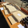 Unfinished wooden boxes and boards displayed on a table at an outdoor market stall.